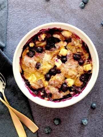 Creamy bread pudding with blueberries in a white bowl