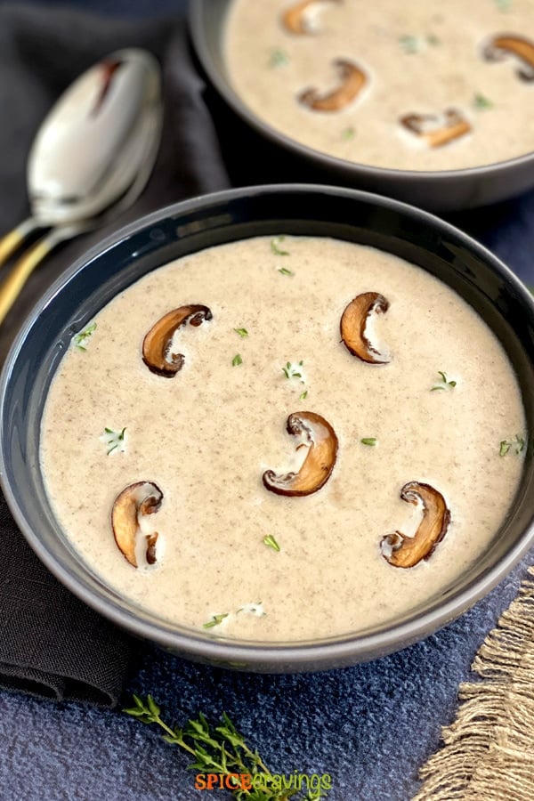 Two bowls of Creamy Mushroom Soup garnished with browned mushrooms