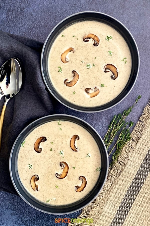 Two bowls with cream of mushroom soup garnished with thyme
