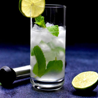 low carb mojito in highball glass garnish with lime slice with muddler and lime on the side