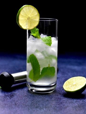 low carb mojito in highball glass garnish with lime slice with muddler and lime on the side