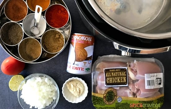 Indian spices in metal bowls, can of coconut milk, rice, packaged chicken thighs, Instant Pot