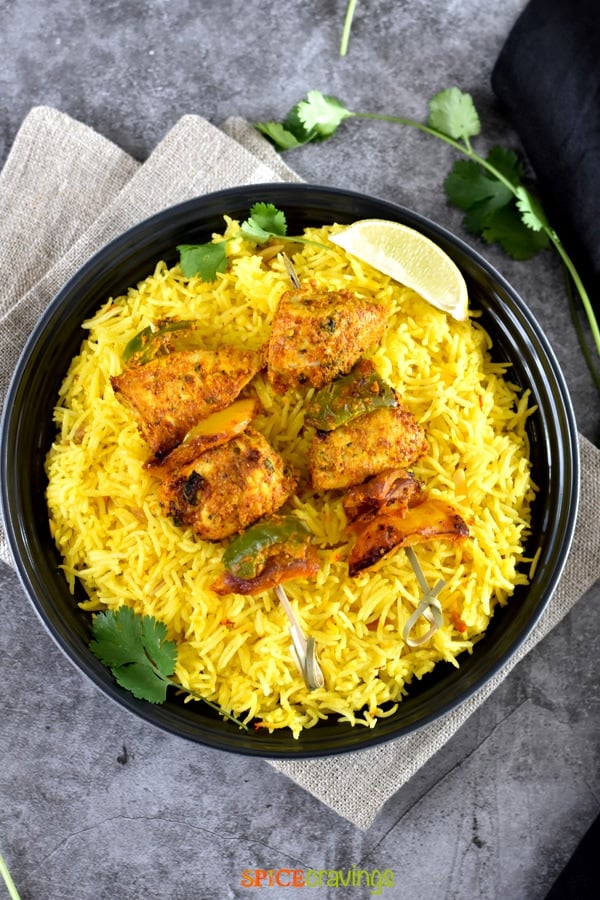 A bowl of Saffron rice with grilled chicken skewers on top