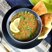 instant pot lentil soup in gray bowl on blue plate with pita on the side