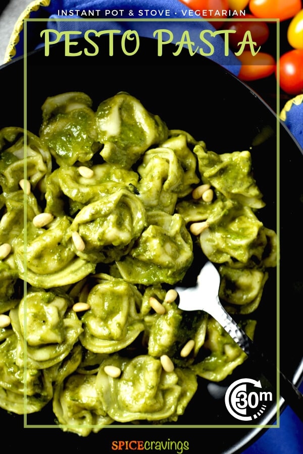 tortellini pesto pasta in black bowl with fork garnished with pine nuts