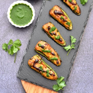 baked samosa stuffed jalapeno poppers on charcoal board with cilantro and tamarind chutney in two white bowls
