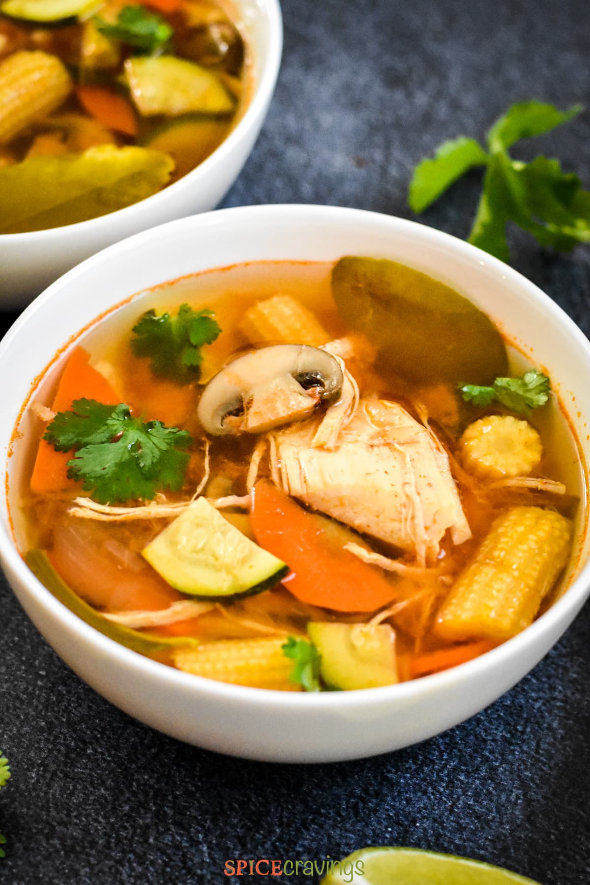 A bowl of tom yum soup with chicken, mushrooms and baby corn