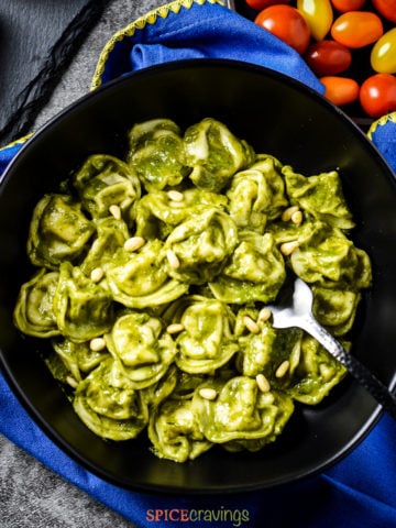 Bowl of pesto tortellini with a side of cherry tomatoes