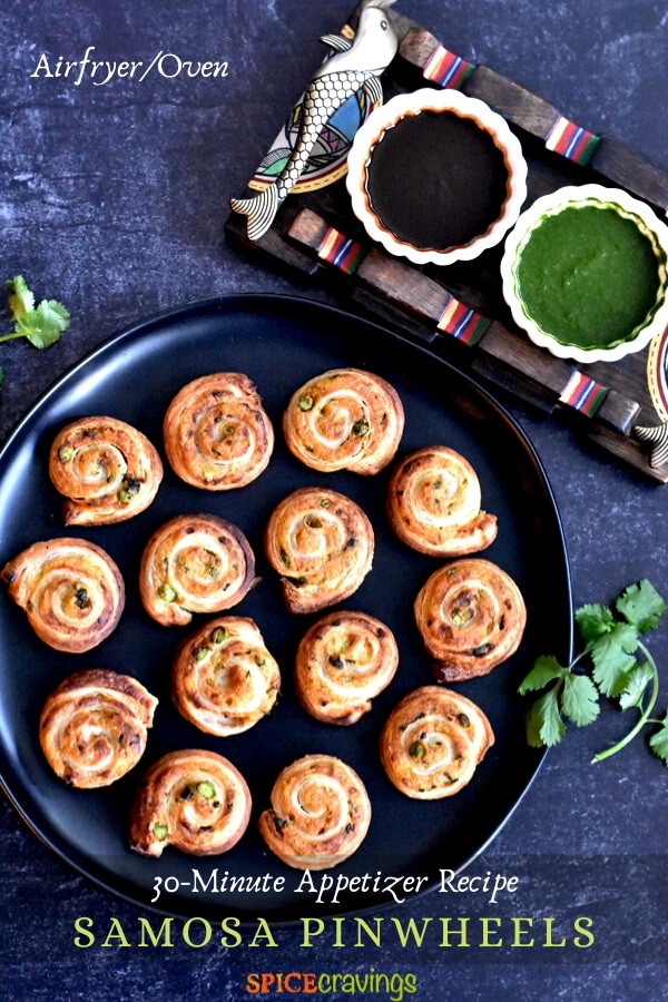 puff pastry samosa pinwheels on black serving plate with cilantro and tamarind chutney in two small white bowls