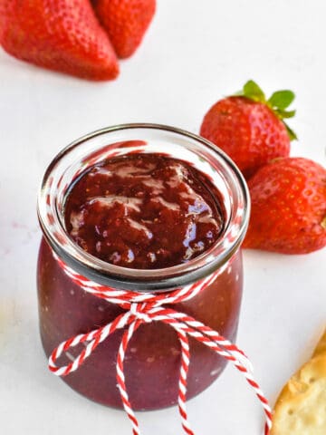 strawberry preserves in glass jar with fresh strawberries