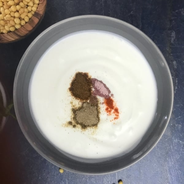 yogurt and spices in gray bowl with boondi in bowl on side