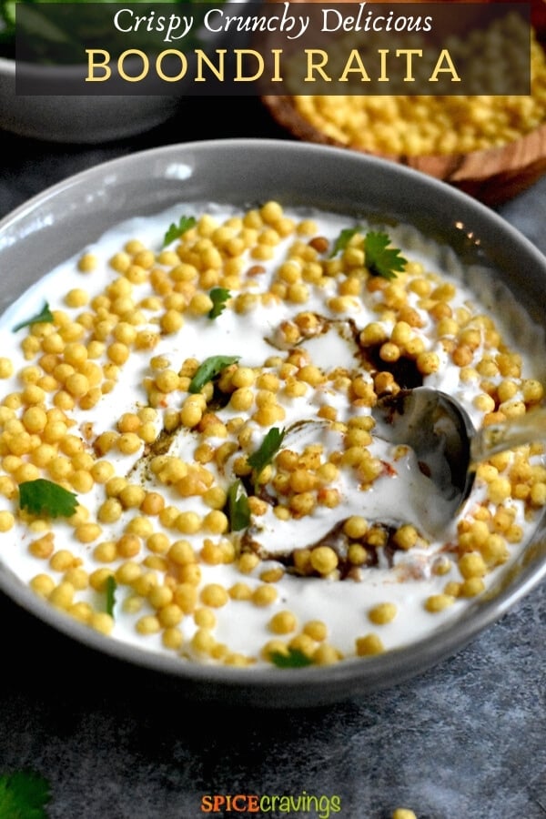 spiced yogurt sauce with fried chickpea balls in gray bowl with spoon