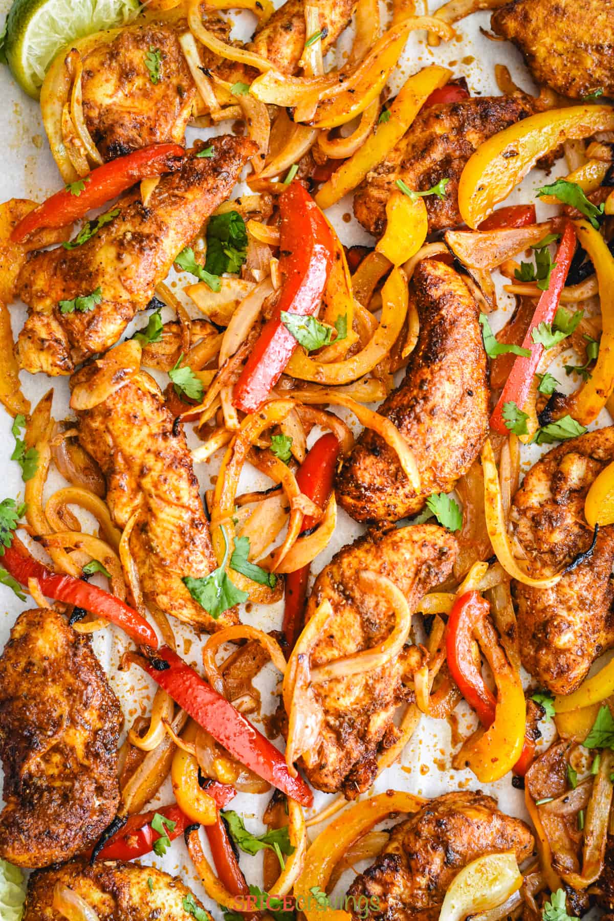 chicken, peppers and onions with mexican seasoning on parchment lined sheet pan