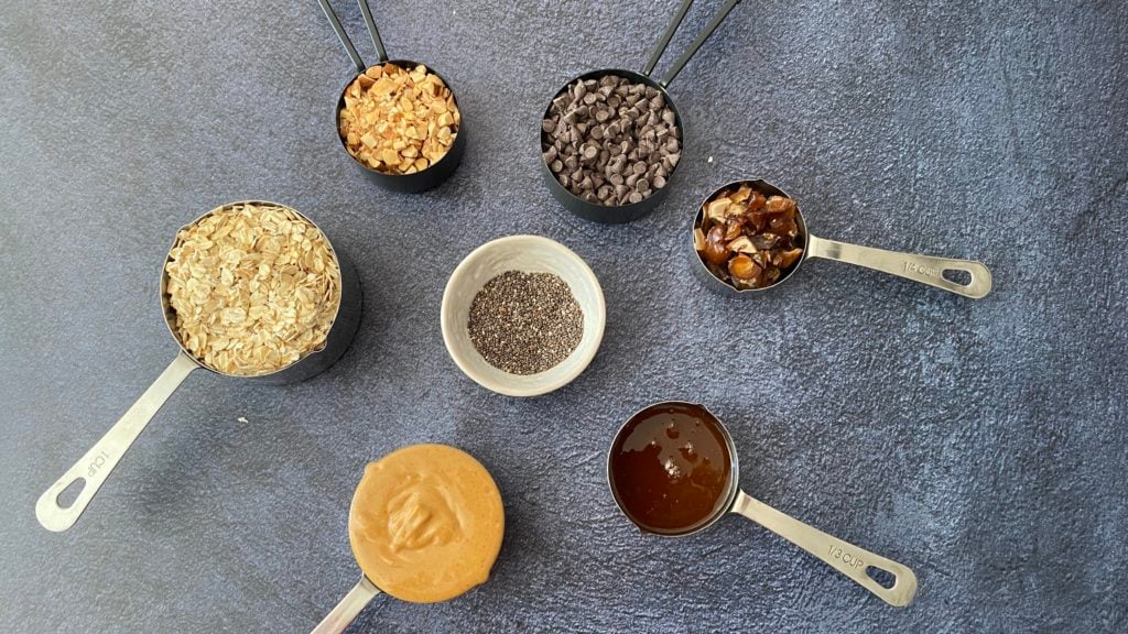 oats, peanut butter, honey, almonds, chia seeds, dates in measuring cups
