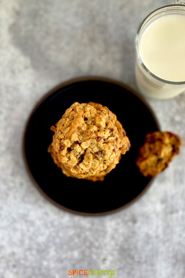 oatmeal cookies on black plate with glass of milk
