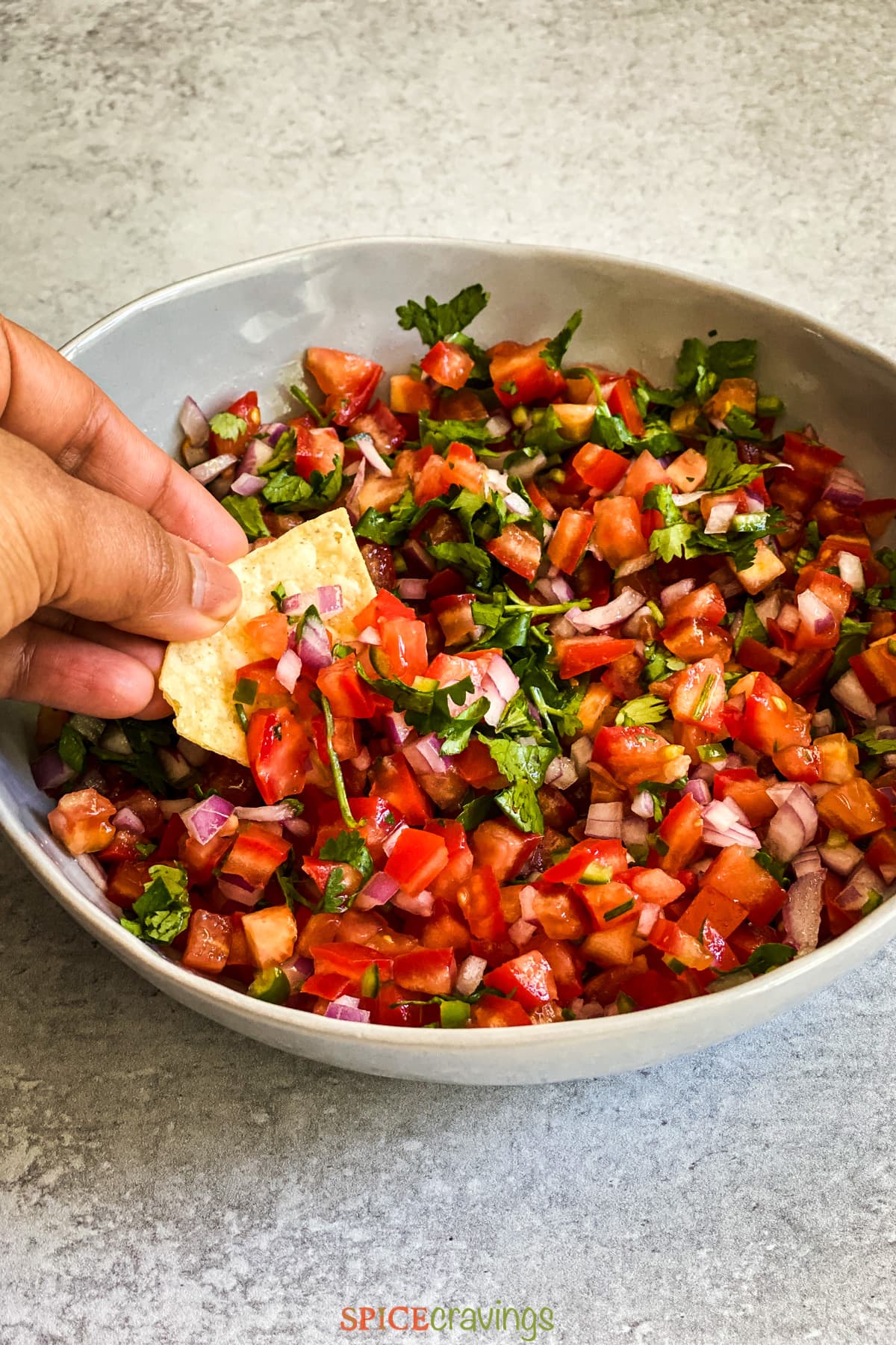 Hand dipping chips in pico de gallo