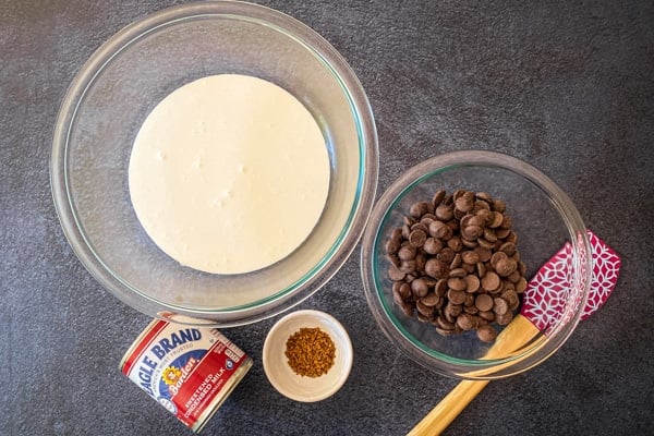 chocolate chips and heavy cream in glass mixing bowls with spatula and can of condensed milk