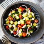 Bowl with halved tomatoes, cucumber, red onions and feta cheese crumbles