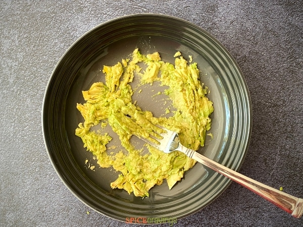 mashed avocado in stoneware bowl with fork