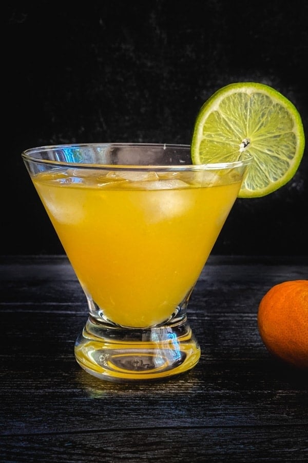 An orange skinny margarita cocktail garnished with a lime wheel