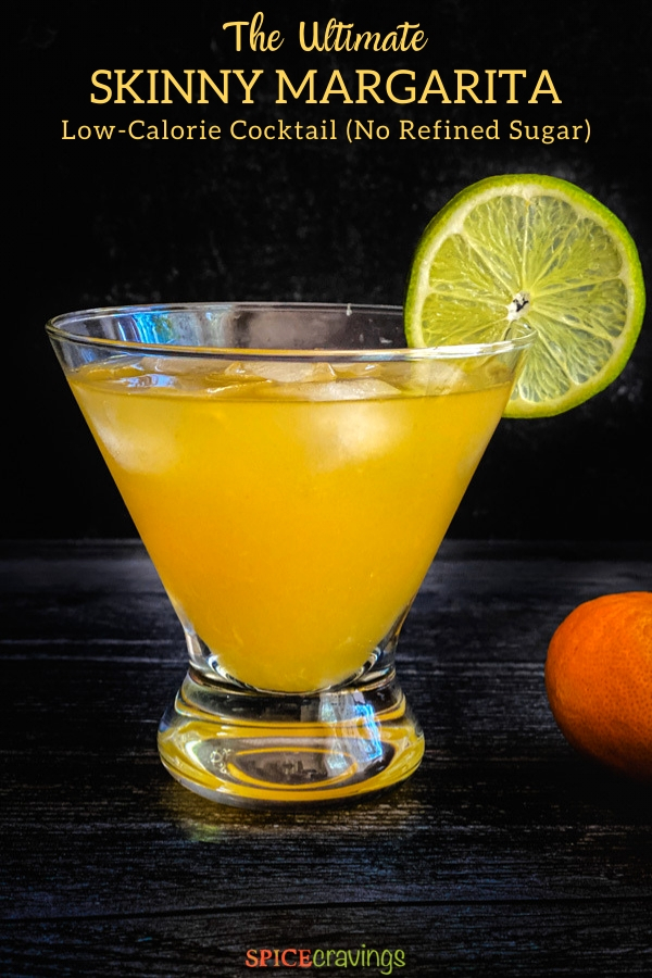 Orange drink in a glass garnished with a lime wheel