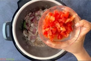 Adding chopped tomato to sautéed onions