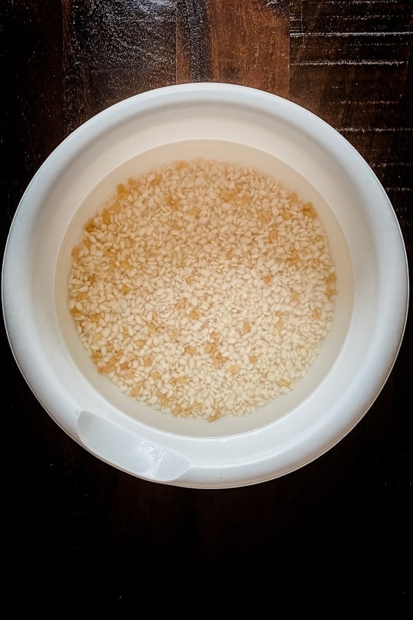urad dal and fenugreek seeds soaking in water in white bowl