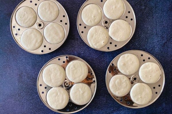 Four idli molds filled with batter