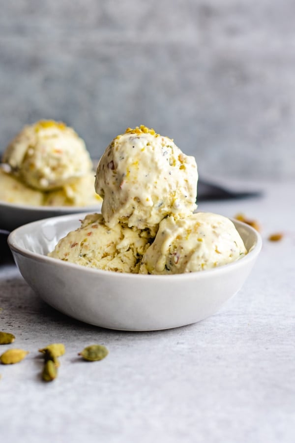 scoops of kulfi ice cream in two white bowls topped with chopped nuts