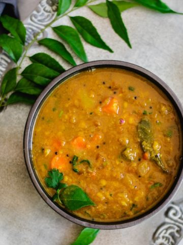 instant pot sambar recipe in gray bowl with curry leaves on the side