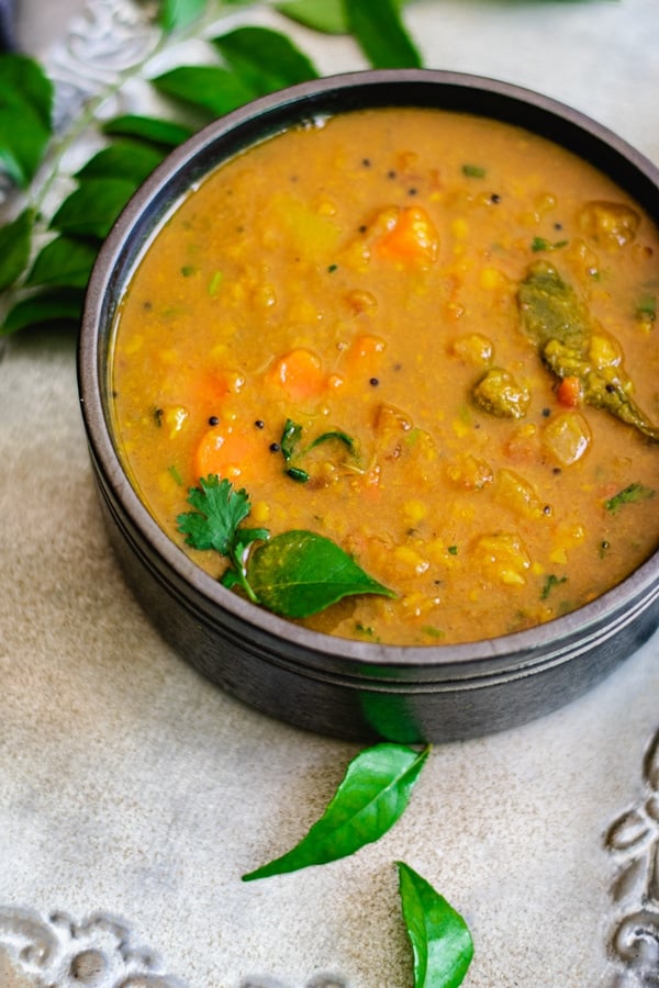 split pigeon pea and lentil soup in gray bowl with curry leaves on the side