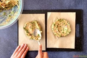 spoon shaping spiced chicken burgers on parchment paper liners