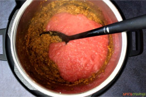 Adding tomato puree to the pot