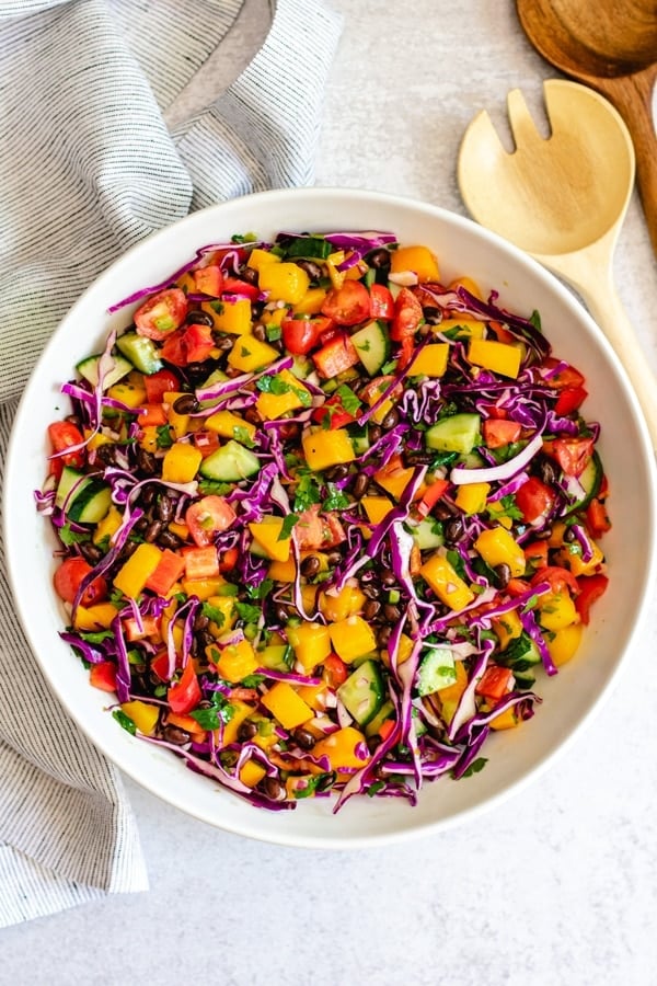 mango salad recipe with lime dressing in white bowl with wooden spoon