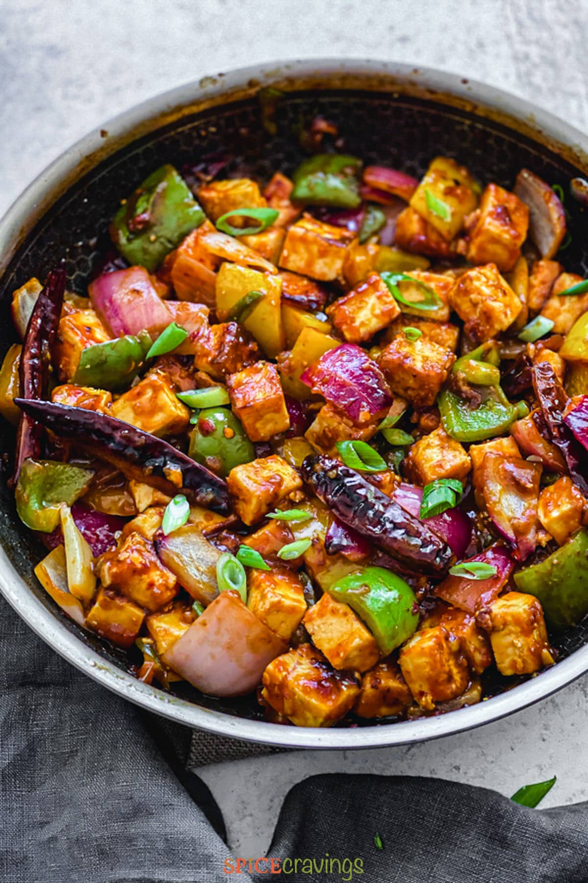 crispy paneer cubes with green pepper and onion chunks in skillet