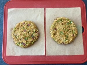 two round taco burger patties on parchment paper squares on cutting board