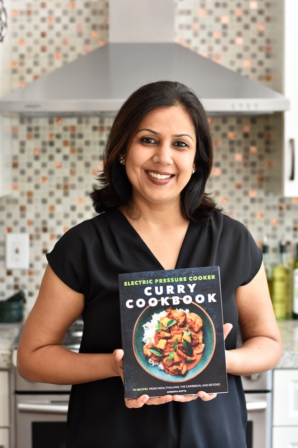 Aneesha, Author of the Curry Cookbook holding the book in her hand