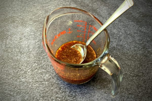 Asian sauce in measuring cup with spoon