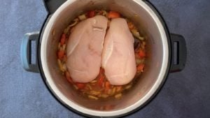 two chicken breasts on tomato-onion mix in Instant Pot