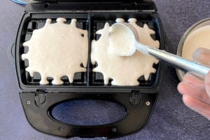 pouring uttapam waffle batter into waffle maker