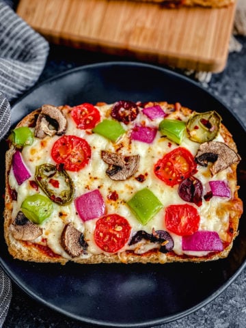veggie supreme bread pizza toast on black plate with blue napkin