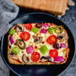 easy pizza bread recipe with fresh vegetables on black plate with blue napkin