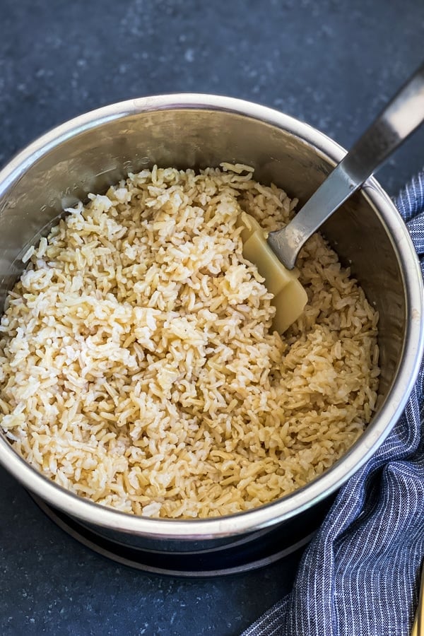 cooked brown rice in a stainless steel bowl with spatula