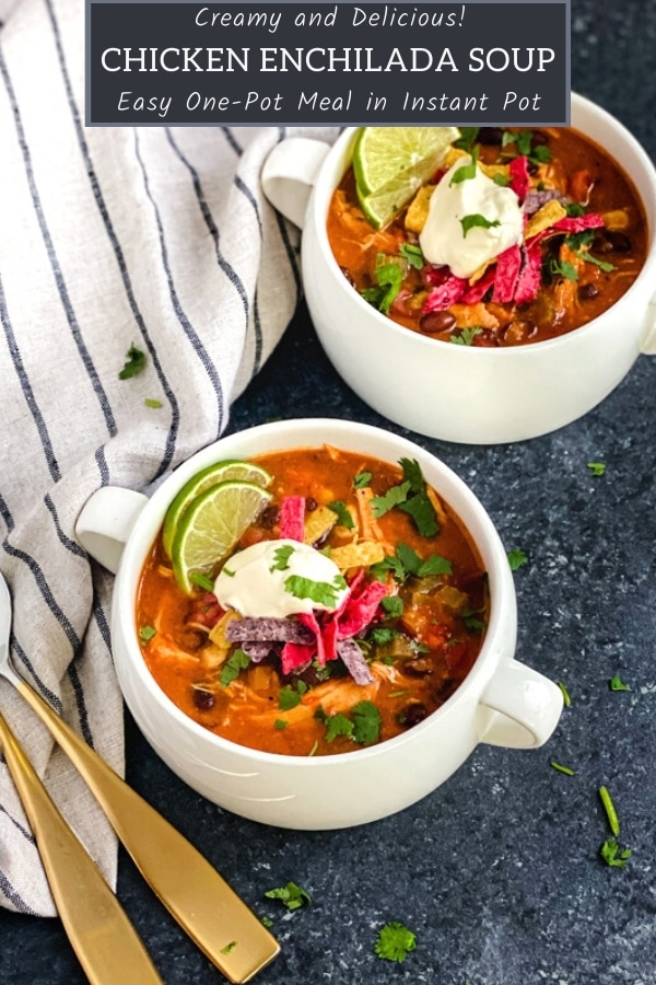 cheesy enchilada soup in two white soup crocks topped with sour cream and tortilla strips