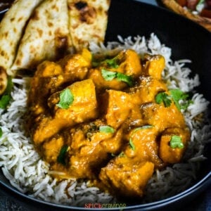 Chicken tikka masala with naan and rice in black bowl