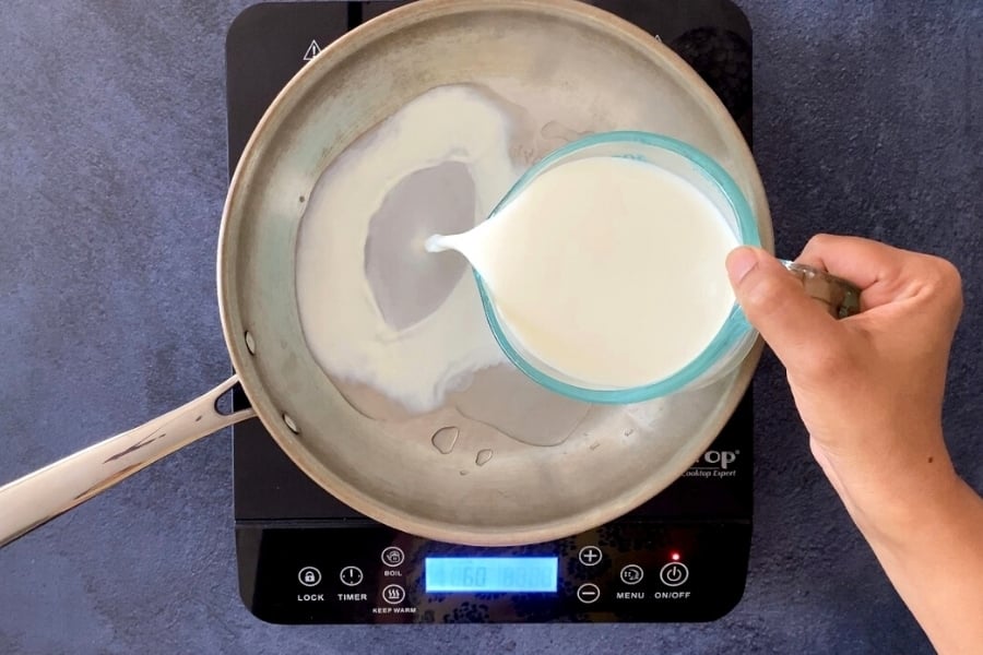 pouring milk into stainless steel saucepan from measuring cup