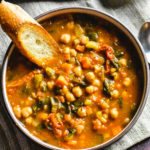 A bowl of moroccan chickpeas soup with a slice of toasted bread