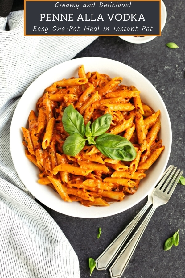 penne vodka recipe in white bowl garnished with fresh basil with two forks on the side