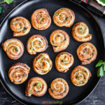 Samosa flavored puff pastry pinwheels on a black plate