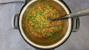 chana masala filling with fresh cilantro and black spoon in instant pot